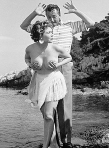 Simone Silva posing topless with Robert Mitchum at the 1954 Cannes festival.